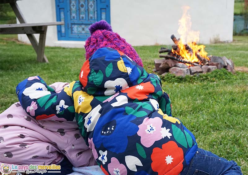 enfant devant une yourte et un feu de bois 