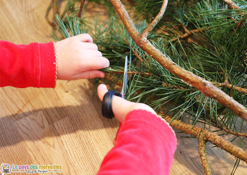 Couper des branches des branches de pin pour faire une couronne de Noël