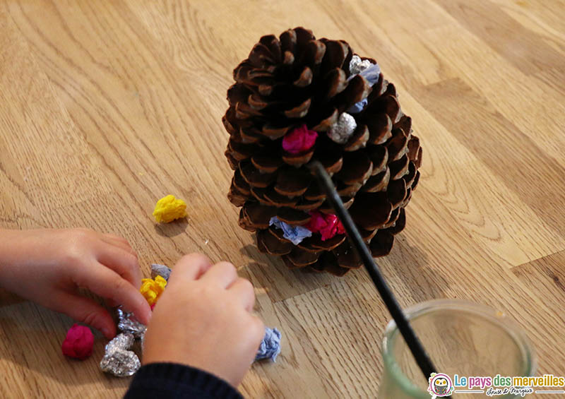 coller des boulettes de papier sur une pomme de pin