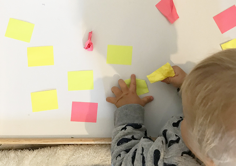 bébé attrape des post-it collés sur un plateau