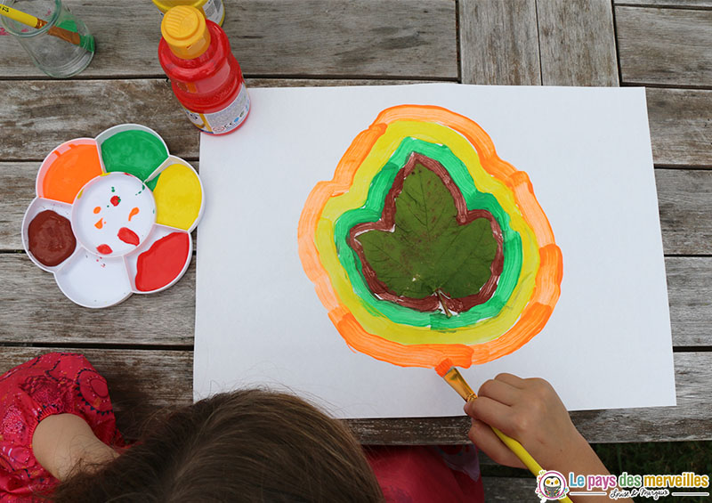 Enfant de primaire qui peint le contour d'une feuille d'arbre