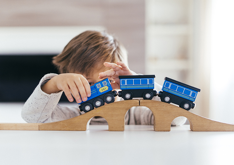 Enfant qui joue avec un train en bois bleu