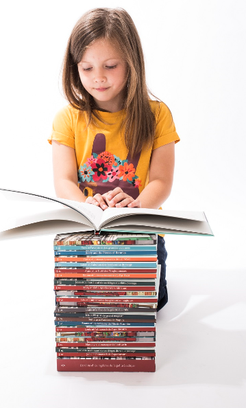 Petite fille qui lit une pile de livres