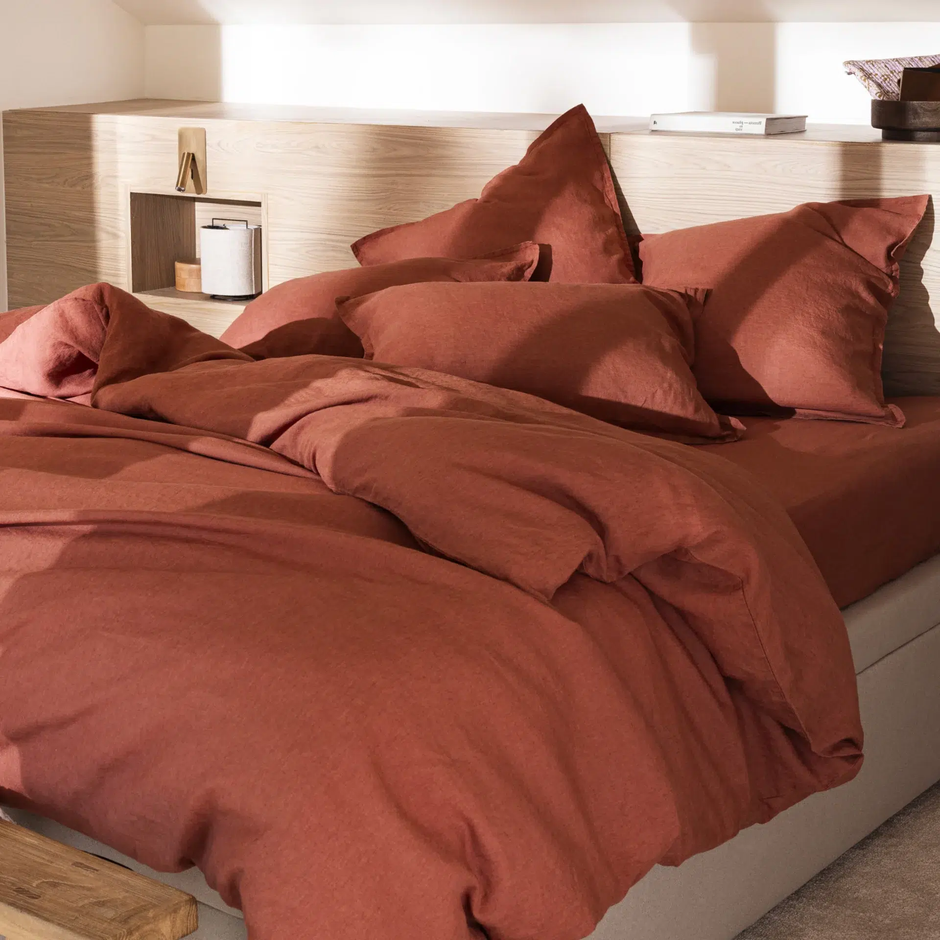 Parure de lit terracotta en lin lavé avec housse de couette et oreillers dans une chambre chaleureuse