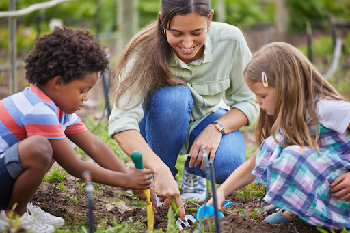 Enfants jardinant dans un potager avec un adulte