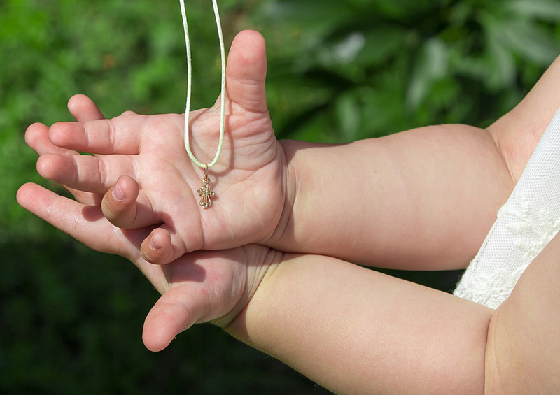 Médaille de baptême dans les mains d'un bébé