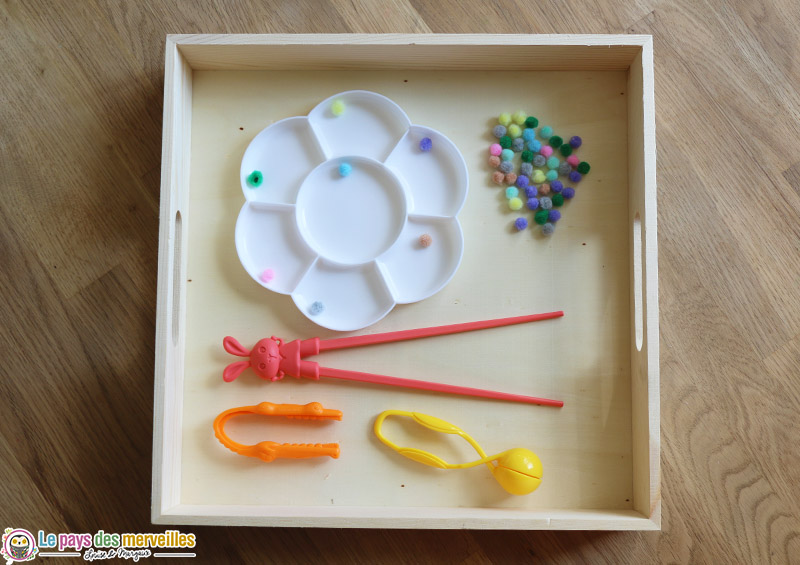 plateau de motricité fine avec des pompons colorés