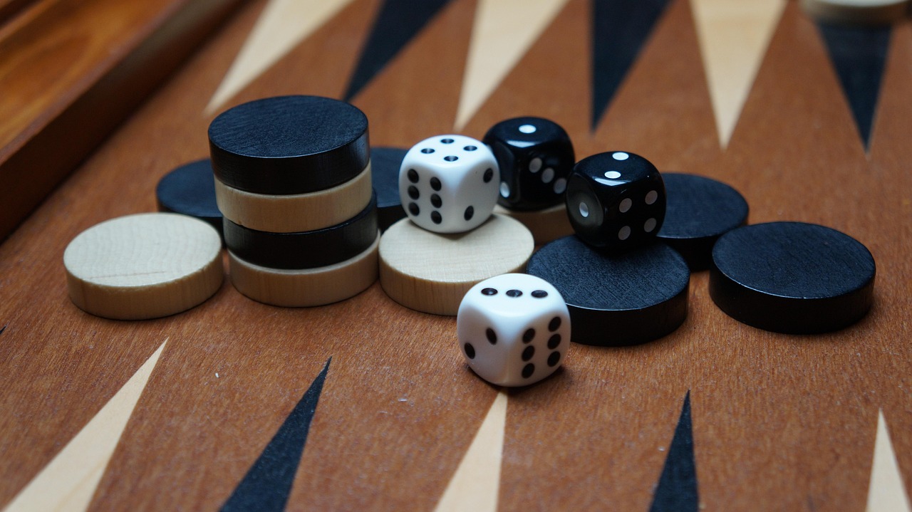 Pions noirs et blancs avec des dés sur un plateau de backgammon en bois