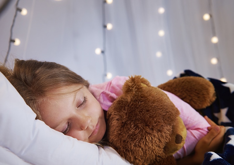 petite fille qui dort paisiblement avec son doudou et lumière douce